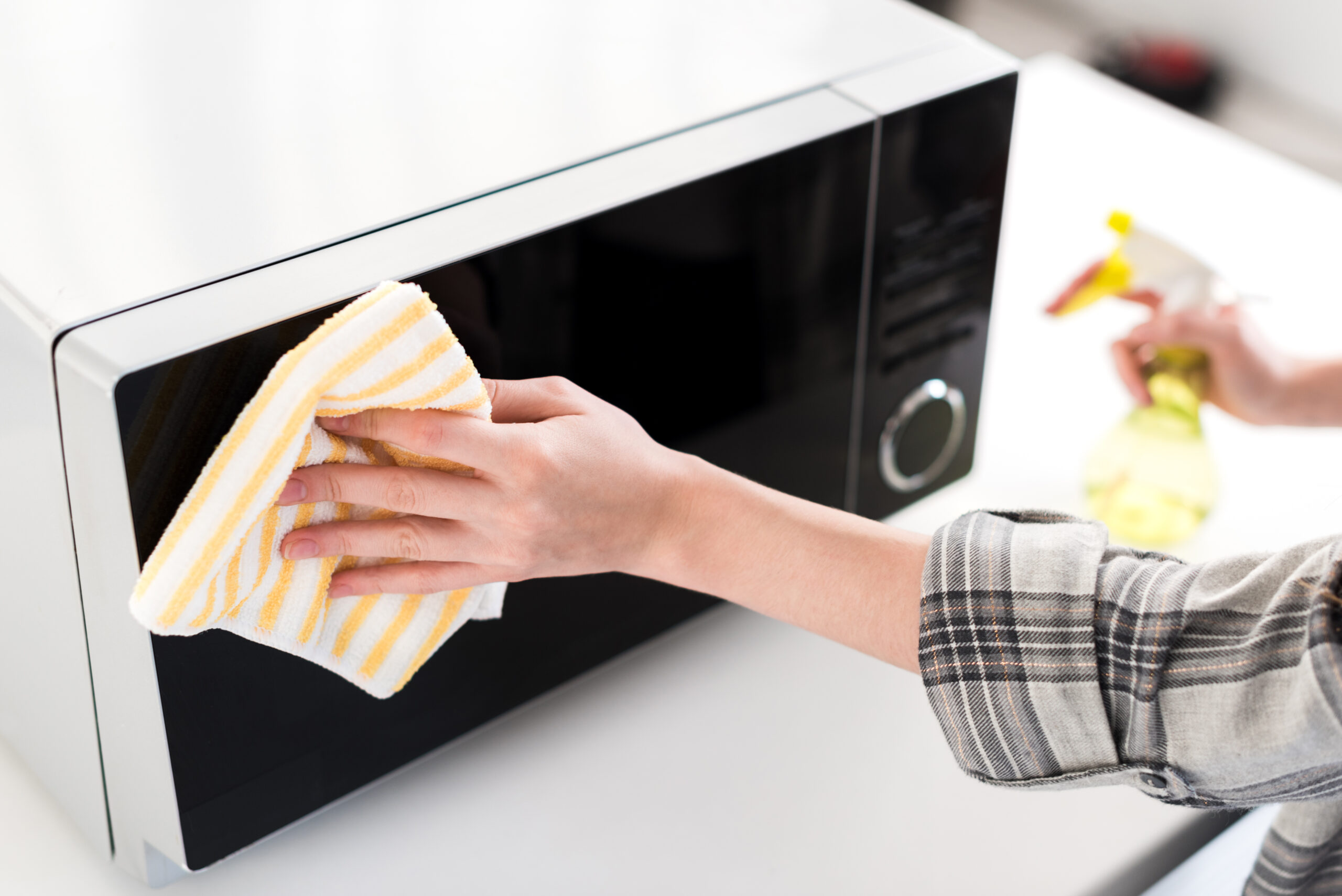 cropped view of woman cleaning microwave with rag in kitchen